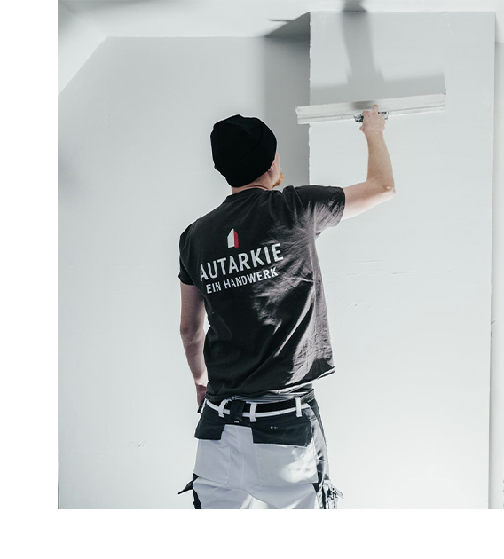 Mann mit einem Spachtel an einer weißen Wand